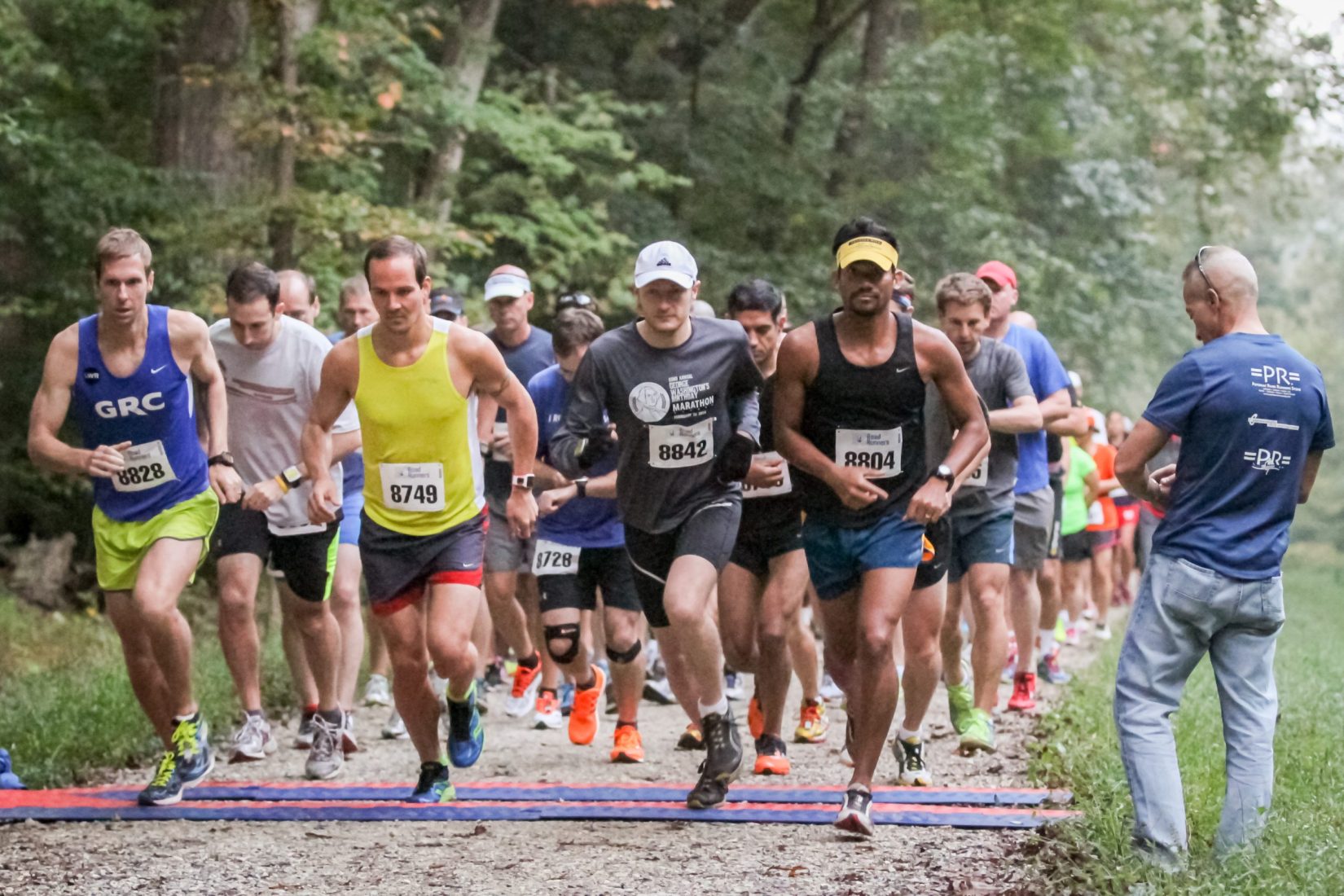 a group of runners crossing the start line of the National Capital 20 Miler on the C&O Towpath