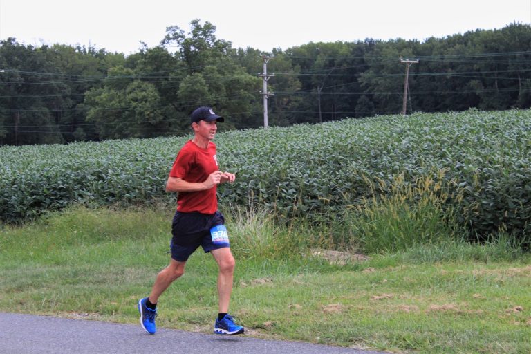 Alan Dixon running in a DC Road Runners race on a paved trail with green grass in the background