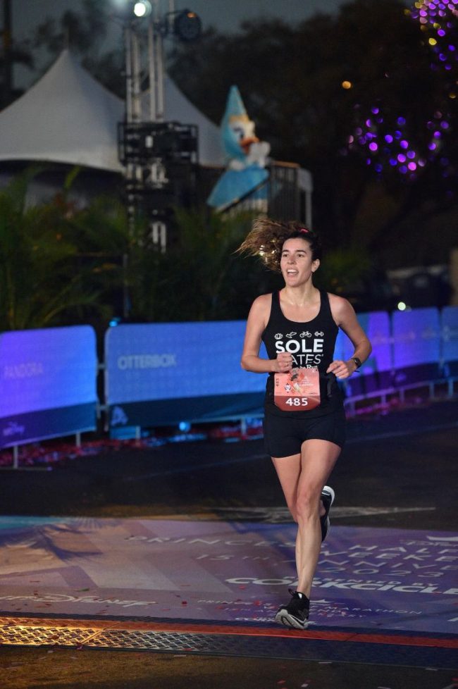 Bailey Estes crossing the finish line at a nighttime road race
