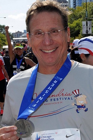 Gary Morgans smiling and holding his finisher medal after running the Chicago Marathon