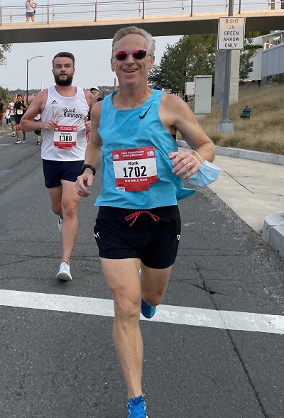 Mark Bourgeois racing on a road in a light blue singlet and matching blue shoes