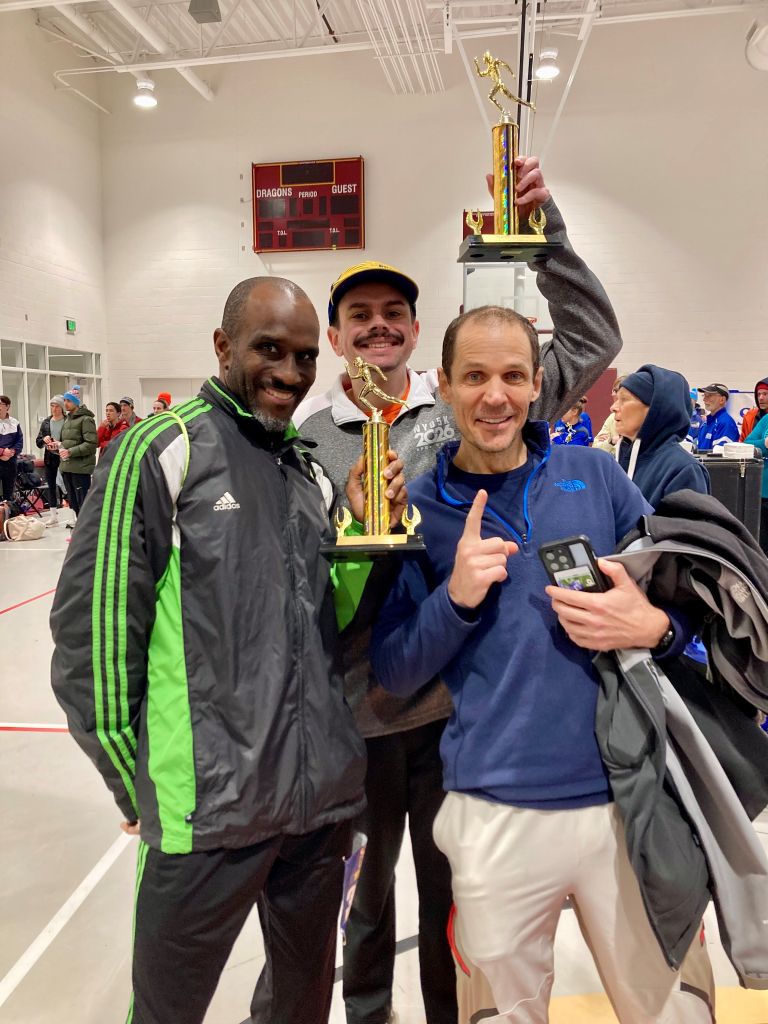 three DC Road Runners members smiling and celebrating while holding the first place male team and first place male under 40 team trophies