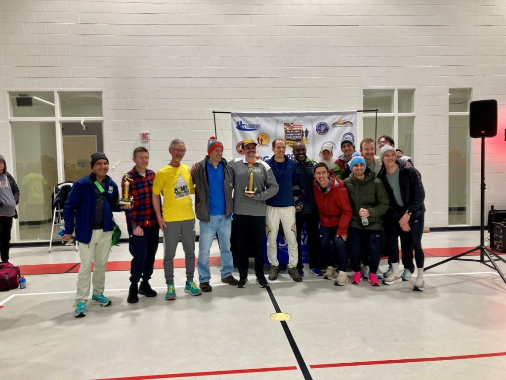 a group of DC Road Runners members standing in a line while holding the first place male team and first place male under 40 team trophies