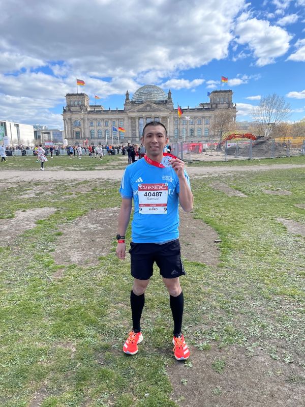 Samuel Woo holding a finisher medal from the Berlin Half Marathon
