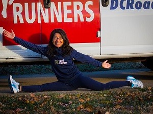 Jennifer Vu doing the full splits while wearing DC Road Runners gear in front of the DC Road Runners van