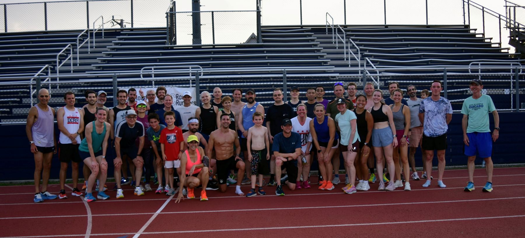 participants in the 2025 DC Road Runners Global Running Day Mile Time Trial standing in a group on the Washington-Liberty High School track in front of metal bleachers