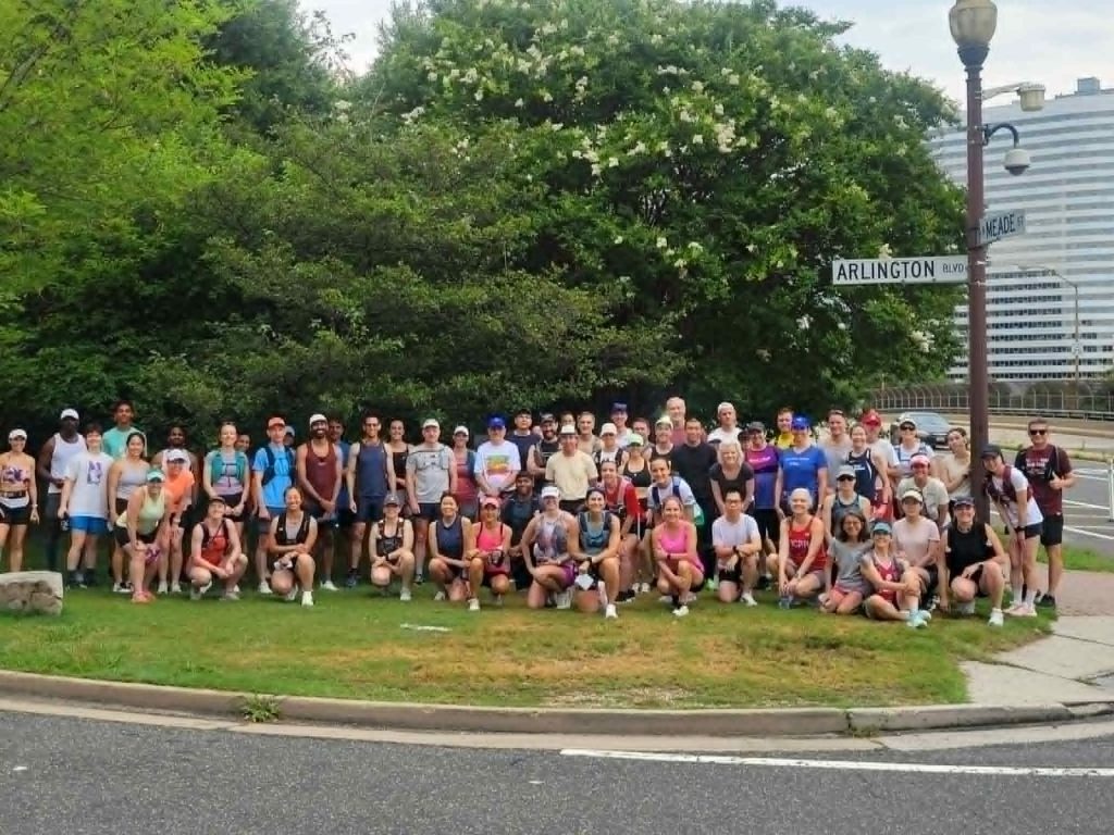 a large group of DC Road Runners members posing for a group photo on the grass in North Meade Street Park on an overcast Saturday morning